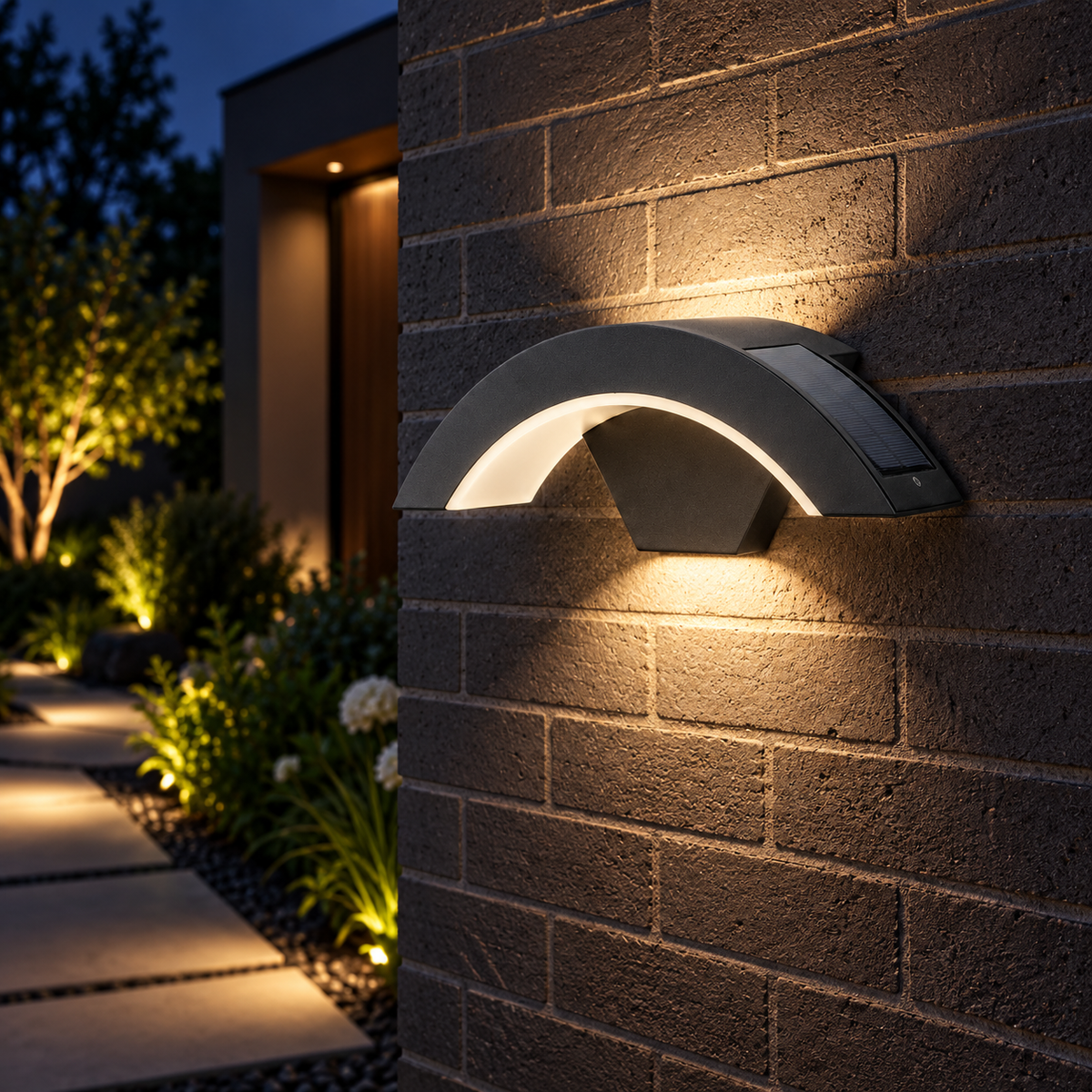 Black arched outdoor wall light illuminating a garden walkway