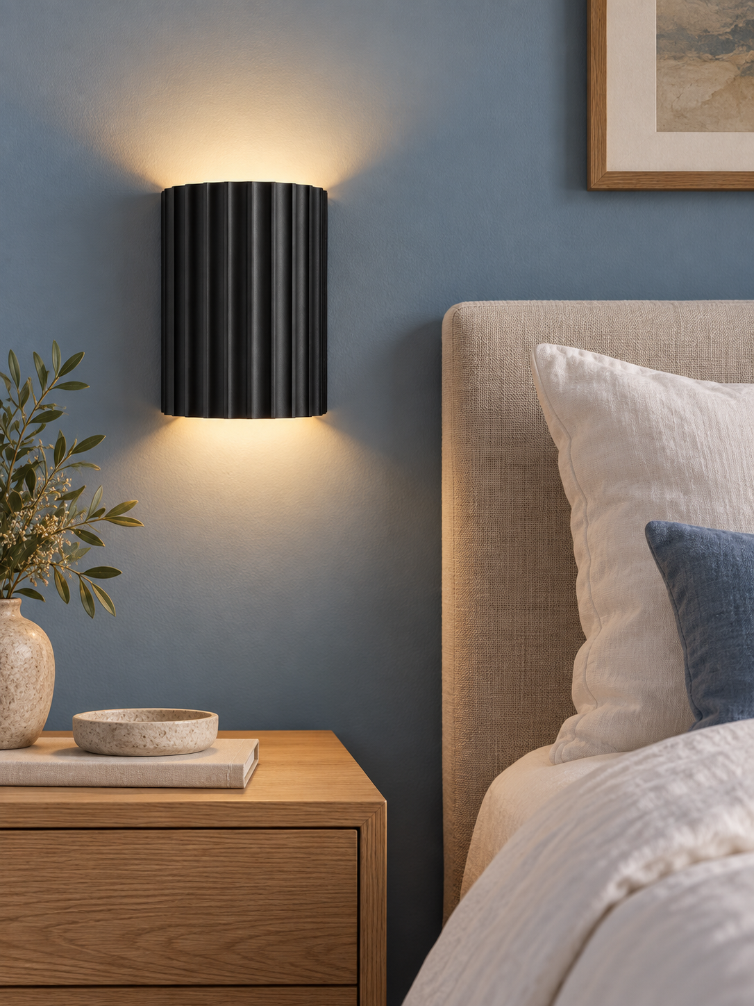 Black resin up and down wall light beside a modern bed