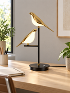 Gold two-bird LED table lamp on a bright home office desk