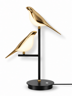 Gold two-bird LED table lamp with soft studio shadow on white background