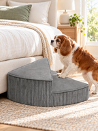 Small senior dog using gray corduroy foam stairs beside a bed
