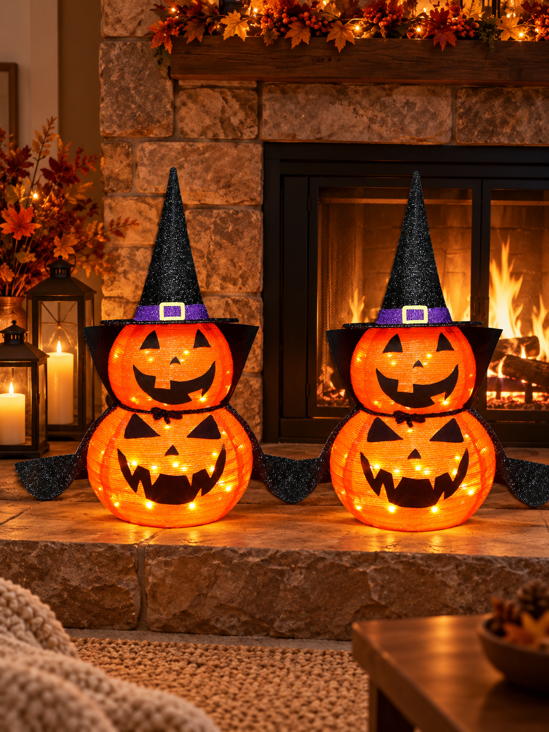 Two illuminated stacked jack-o-lantern decorations on a fireplace hearth