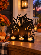 Haunted house metal tealight holder displayed on a covered porch