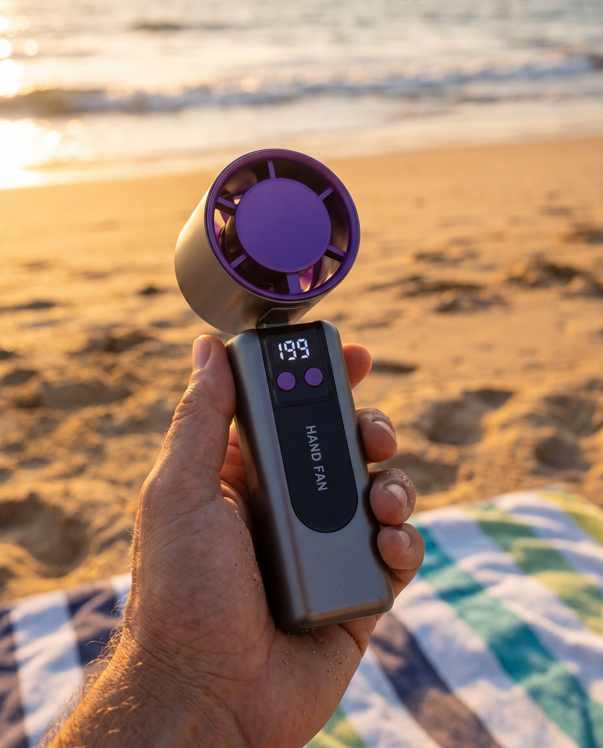 Handheld personal fan in use on a beach, golden hour