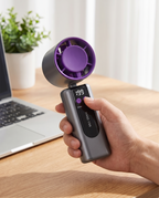 Handheld personal fan in use at an office desk, afternoon