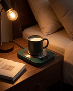 Electric mug warmer in use on a bedroom nightstand, evening