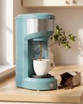 Single-serve coffee maker brewing coffee in a kitchen, early morning