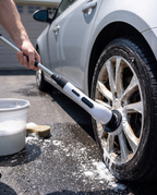 Electric spin scrubber in use cleaning a car wheel, midday
