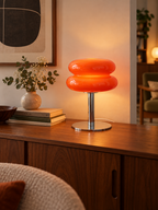 Orange red glass table lamp on a walnut living room sideboard