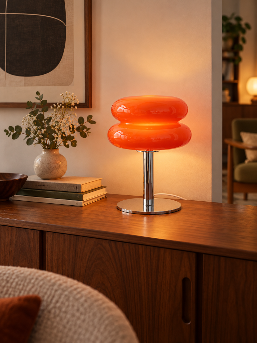 Orange red glass table lamp on a walnut living room sideboard