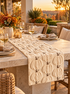 Cream knit pumpkin table runner on a covered outdoor autumn patio table