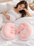 Pink maternity support pillow in a bright bedroom with a pregnant woman