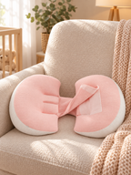 Pink maternity support pillow on an upholstered chair in a warm nursery