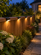 Four solar lights illuminating a garden fence