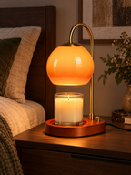 Orange glass candle warmer lamp on a modern bedroom nightstand