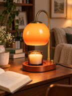 Orange glass candle warmer lamp on a cozy reading desk
