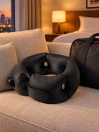Black portable cervical travel pillow in a warm hotel room