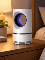 White cylindrical UV mosquito and fly trap glowing on a bedroom nightstand