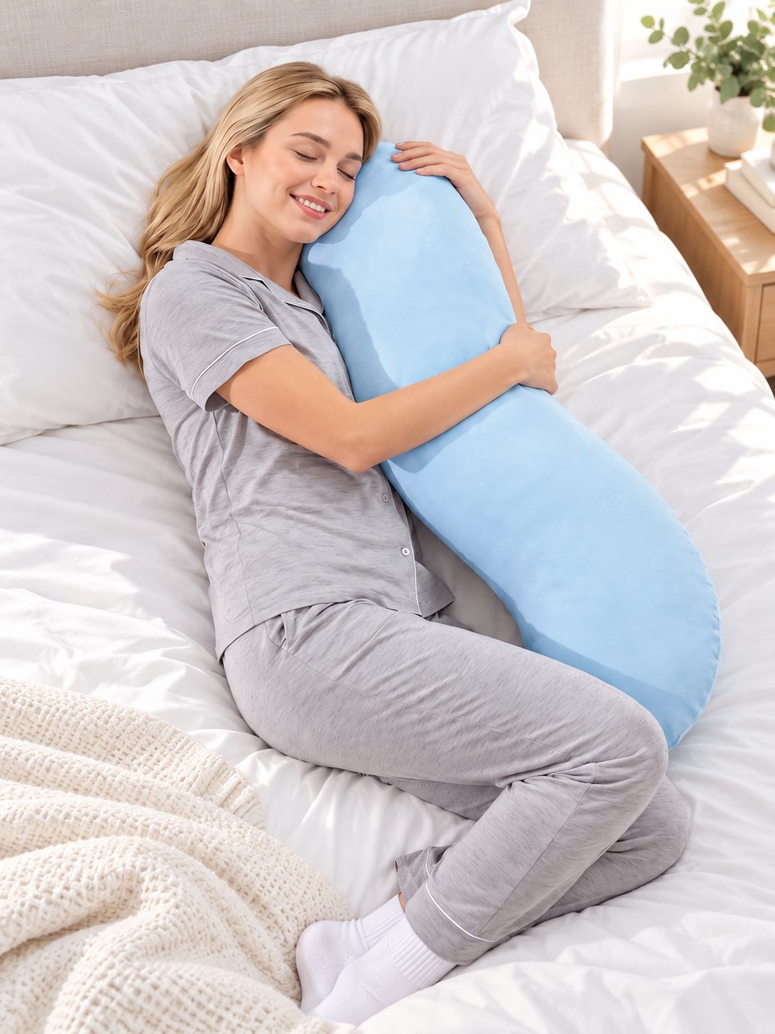 Blue snuggle pillow used by a side sleeper in a bright bedroom