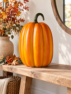 Tall glossy orange pumpkin figure on an autumn entryway bench